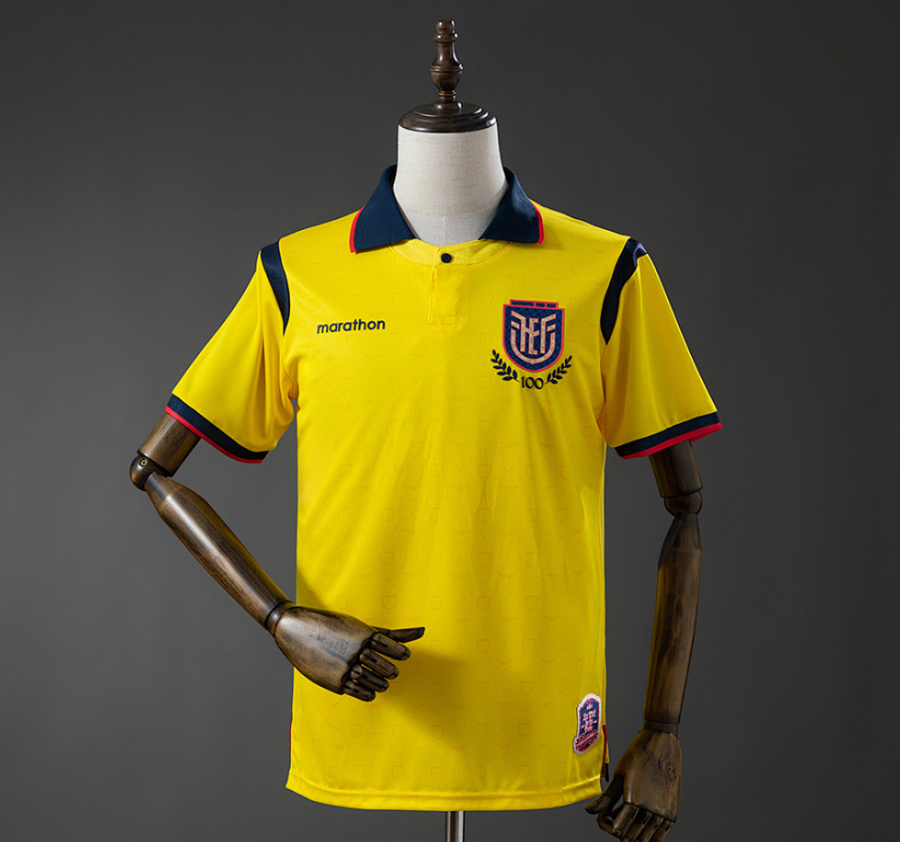 Yellow sports jersey with branding on a mannequin against a gray background